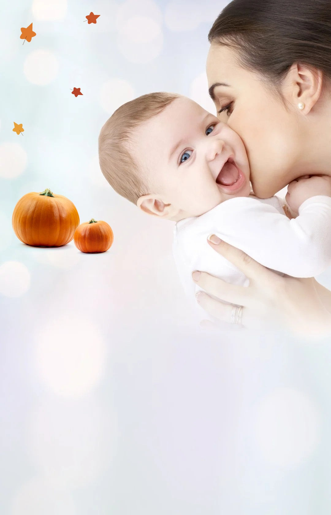 Mother kissing her smiling baby, with pumpkins for Halloween